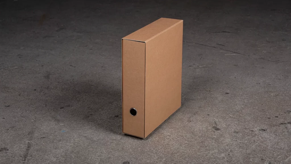 Arkistomappi A4, selkämys 8cm. Kuvassa arkistomappi kotelossaan betonilattialla.