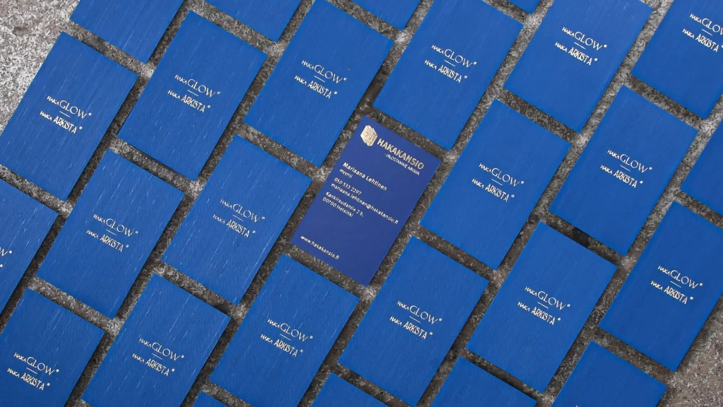 Sinisiä foliopainettuja käyntikortteja vierivieressä. keskellä yksi kortti käännetty