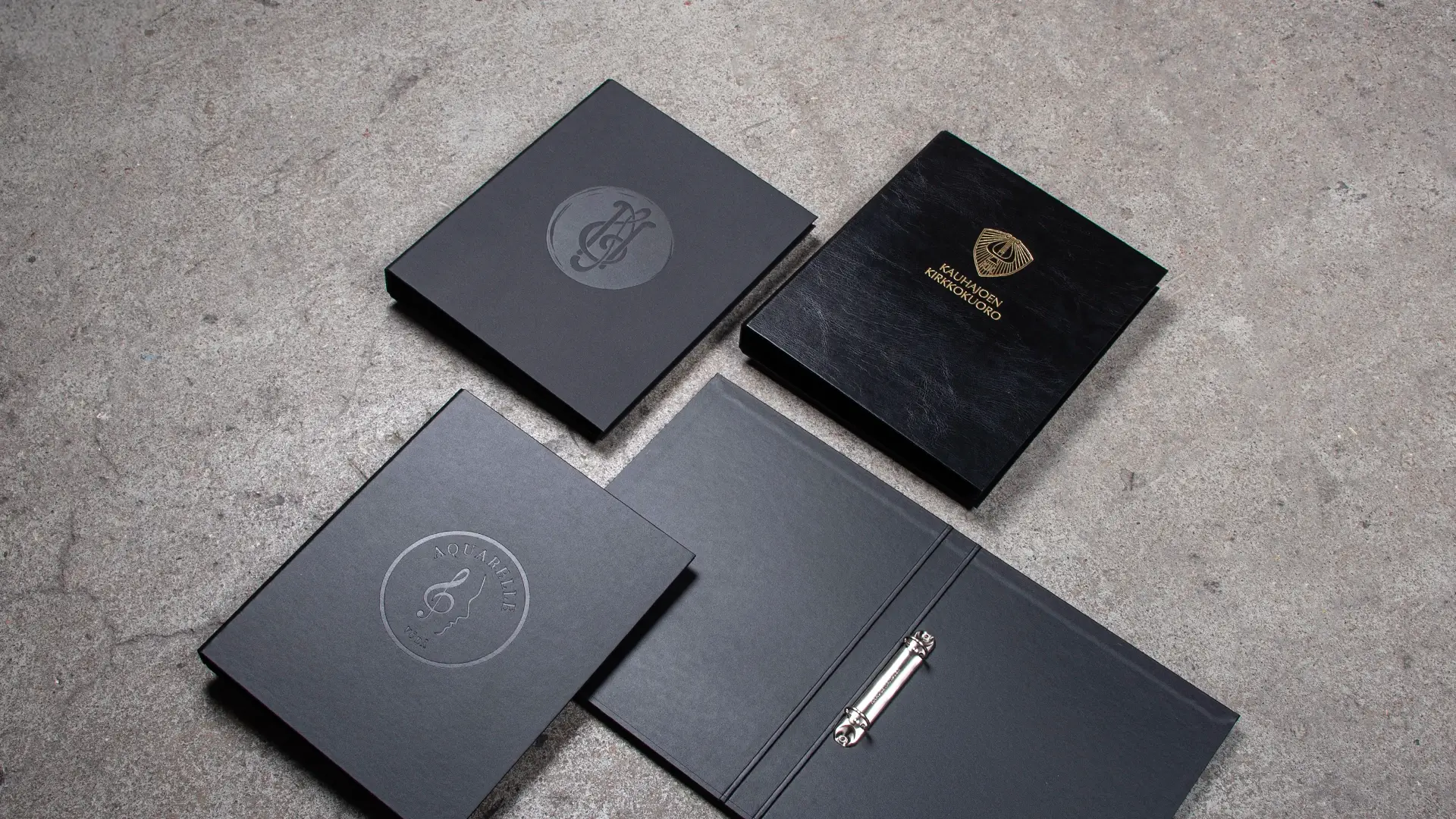 Erilaisia kuorokansioita yhdessä foliopainatus ja kahdessa muussa sokko.